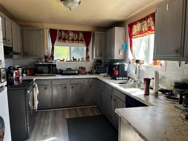 kitchen with a wealth of natural light, tasteful backsplash, dark wood-type flooring, and sink