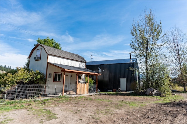 exterior space with a shingled roof, fence, an outdoor structure, and a gambrel roof