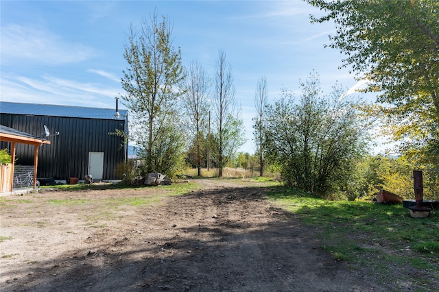 view of road with dirt driveway and an outbuilding