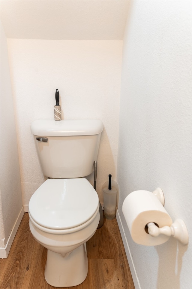 bathroom with toilet, baseboards, and wood finished floors