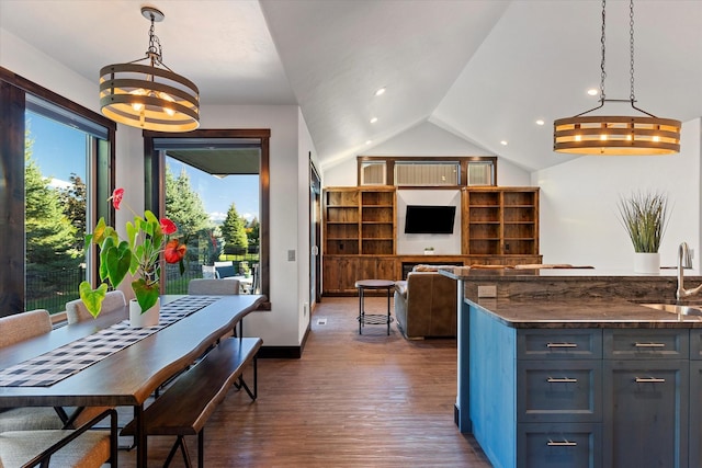 kitchen with dark wood-type flooring, decorative light fixtures, vaulted ceiling, sink, and dark stone countertops