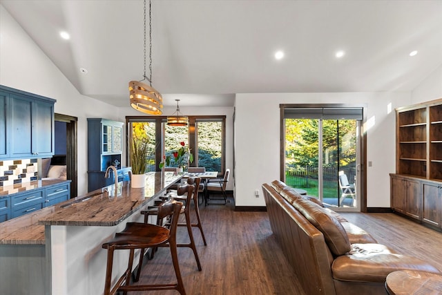 interior space with vaulted ceiling, a breakfast bar, blue cabinets, and pendant lighting