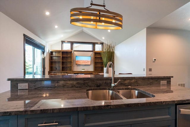 kitchen with hanging light fixtures, sink, vaulted ceiling, dishwasher, and dark stone countertops