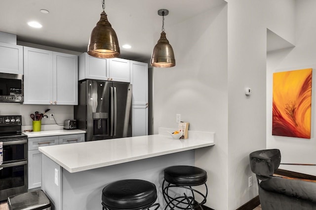 1010 7th St E Unit A, Whitefish, MT 59937 - kitchen featuring appliances with stainless steel finishes, a breakfast bar area, a peninsula, light countertops, and pendant lighting