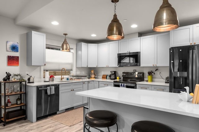 1010 7th St E Unit A, Whitefish, MT 59937 - kitchen featuring black appliances, a sink, a breakfast bar area, light countertops, and hanging light fixtures