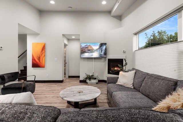 1010 7th St E Unit A, Whitefish, MT 59937 - living room featuring wood finished floors, stairway, recessed lighting, a towering ceiling, and a lit fireplace