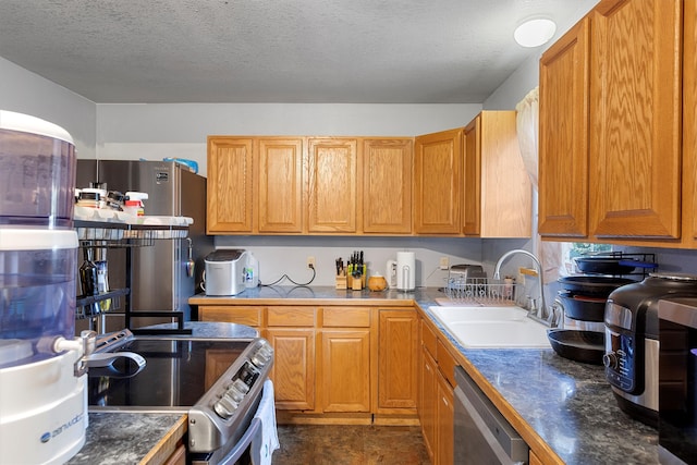 kitchen with a textured ceiling, stainless steel appliances, and sink