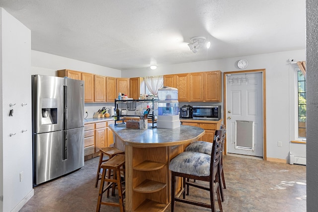 kitchen with a textured ceiling, a kitchen island, baseboard heating, and stainless steel appliances