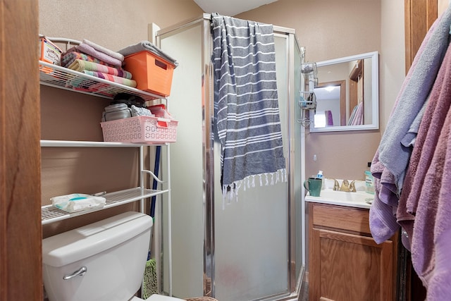 bathroom featuring vanity, a shower with shower door, and toilet