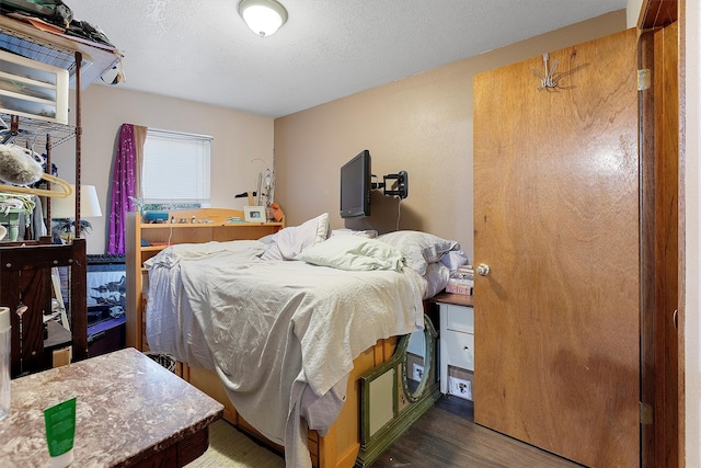 bedroom with a textured ceiling and dark hardwood / wood-style flooring