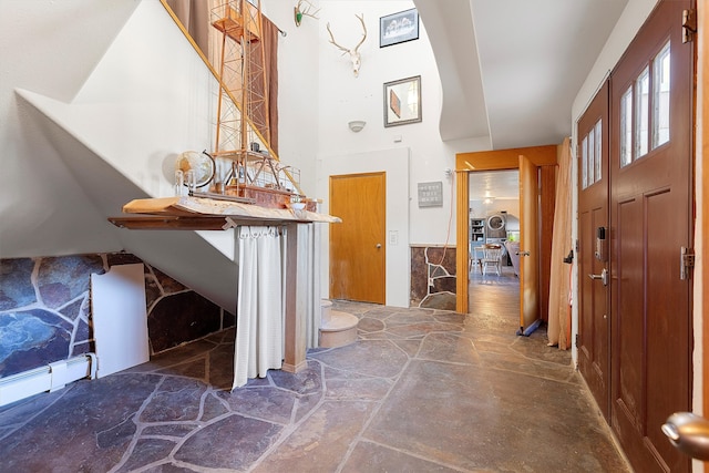 foyer entrance featuring lofted ceiling and a baseboard heating unit