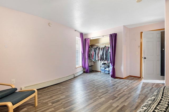 unfurnished bedroom with baseboard heating, a closet, and hardwood / wood-style flooring