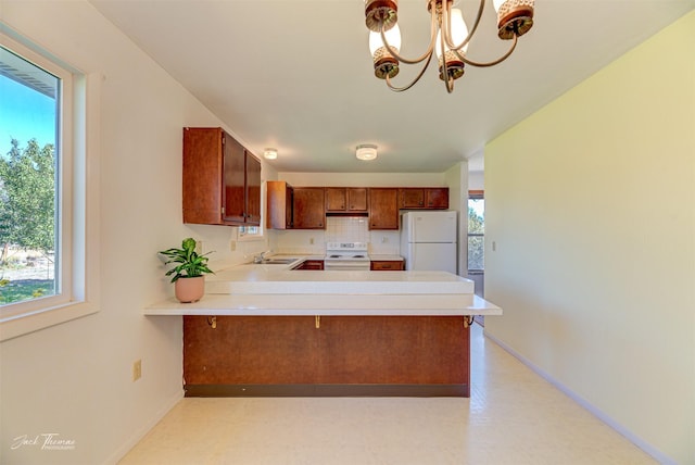 kitchen featuring light floors, light countertops, white appliances, baseboards, and a peninsula