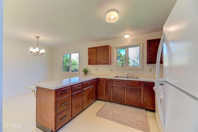 kitchen featuring sink, kitchen peninsula, decorative light fixtures, a chandelier, and white fridge