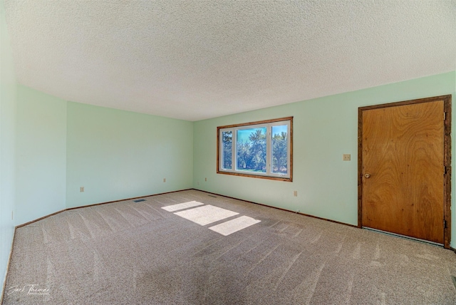 carpeted spare room featuring a textured ceiling and baseboards