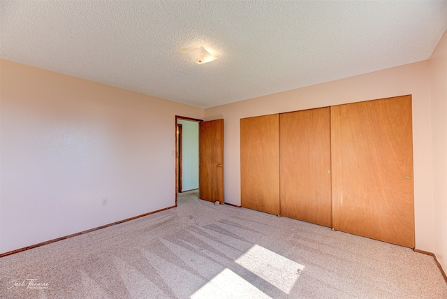 unfurnished bedroom featuring a closet, light colored carpet, and a textured ceiling