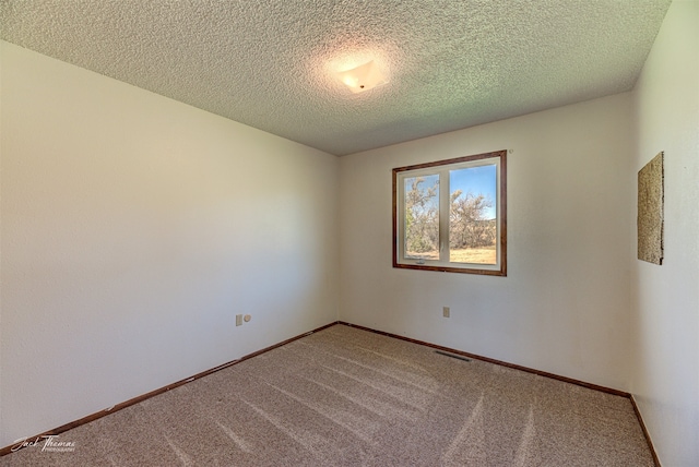 carpeted empty room featuring a textured ceiling