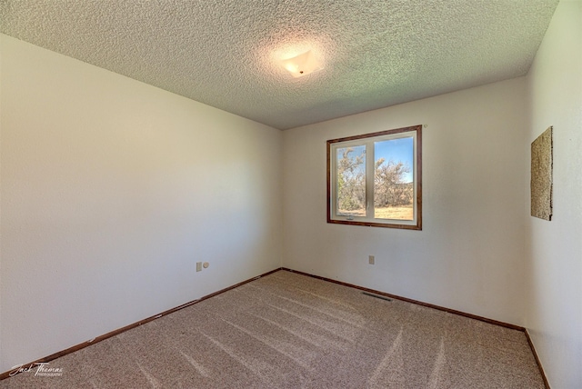 carpeted spare room featuring a textured ceiling, visible vents, and baseboards