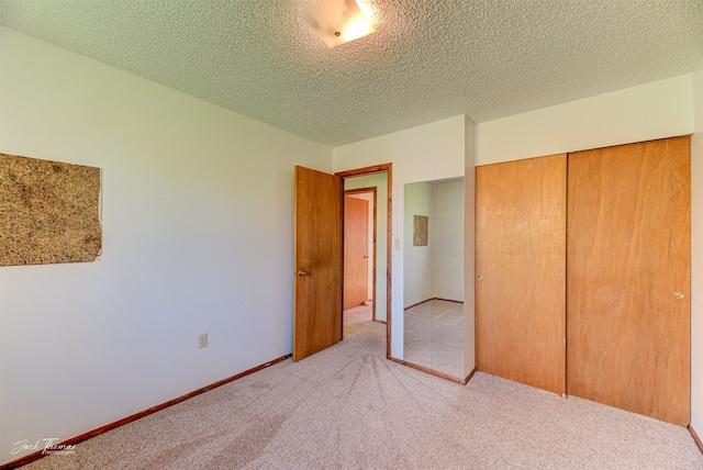 unfurnished bedroom with a textured ceiling, light carpet, and a closet