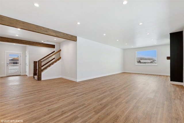 unfurnished living room with beam ceiling and light wood-type flooring