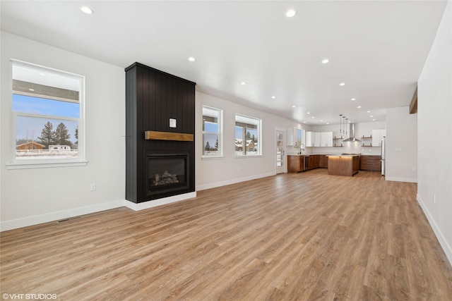 unfurnished living room with light wood-type flooring and a large fireplace