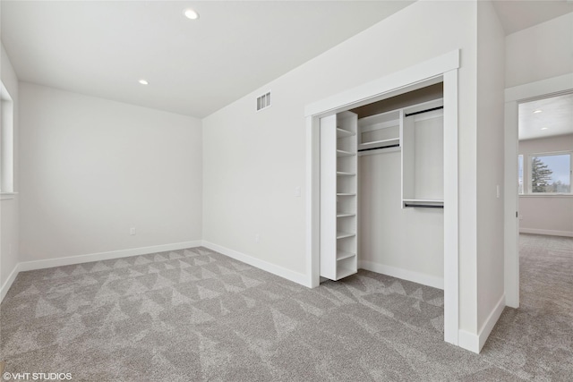 unfurnished bedroom featuring light carpet and a closet