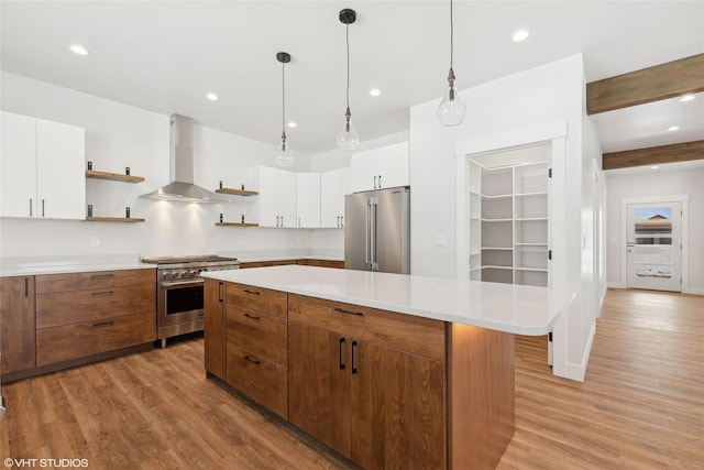 kitchen featuring wall chimney range hood, beamed ceiling, high end appliances, light hardwood / wood-style flooring, and white cabinets