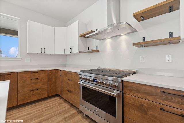 kitchen featuring light wood-type flooring, white cabinetry, extractor fan, and high end stainless steel range