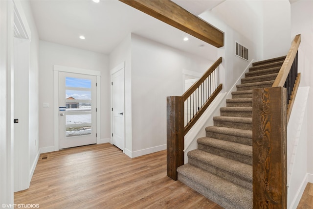 entrance foyer with light hardwood / wood-style floors and beamed ceiling