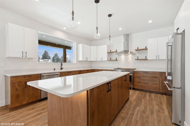 kitchen featuring white cabinets, wall chimney exhaust hood, high quality appliances, and a kitchen island