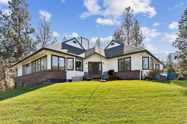 rear view of property featuring a lawn and a sunroom