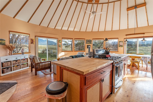 kitchen with ceiling fan, high vaulted ceiling, light hardwood / wood-style flooring, and stainless steel gas range oven