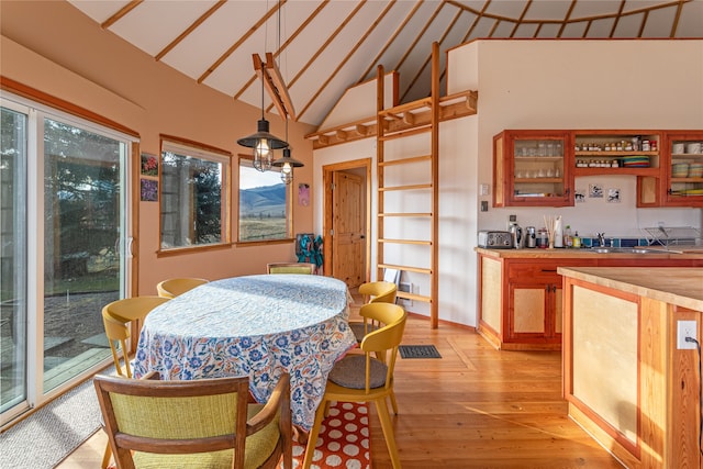 dining space featuring bar, high vaulted ceiling, and light wood-type flooring