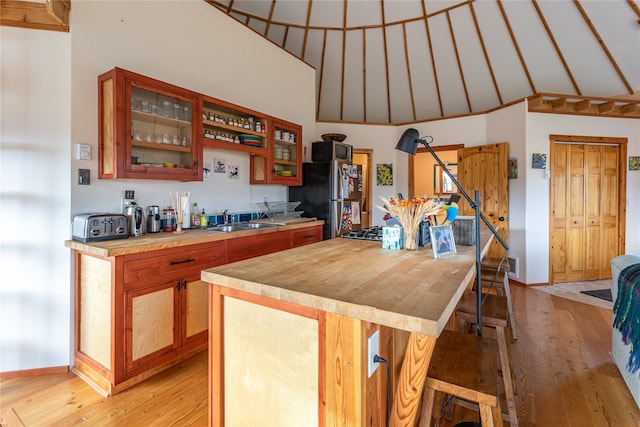 kitchen featuring lofted ceiling, sink, stainless steel fridge, and light hardwood / wood-style floors