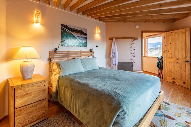 bedroom featuring beam ceiling and hardwood / wood-style floors