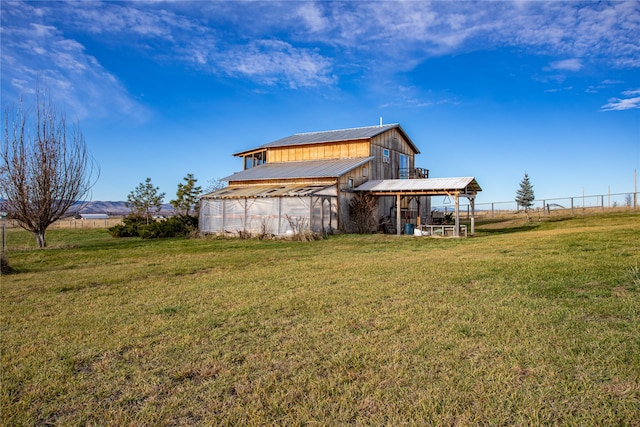 rear view of property featuring a rural view, a yard, and an outdoor structure