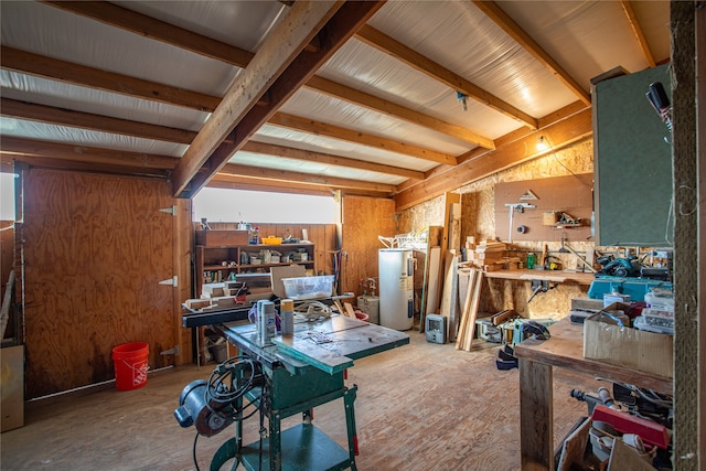 misc room featuring wooden walls, a workshop area, and electric water heater