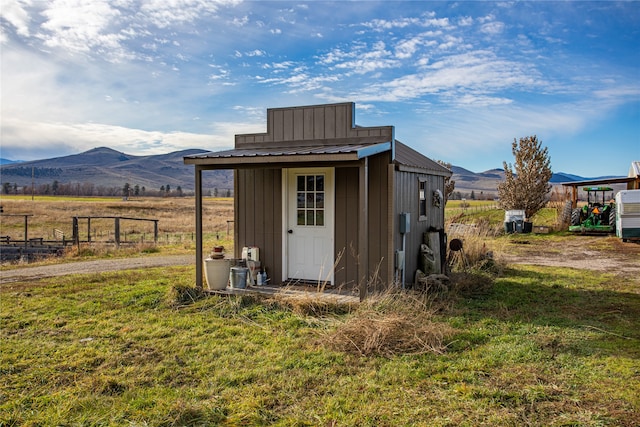 view of outdoor structure featuring a mountain view, a rural view, and a lawn