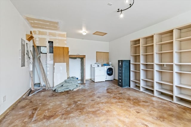 misc room featuring washing machine and clothes dryer, concrete flooring, and electric panel