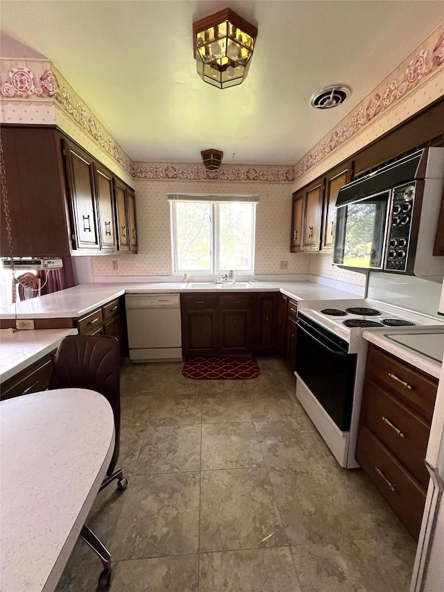 233 4th Ave SW, Cut Bank, MT 59427 - kitchen featuring white appliances, wallpapered walls, healthy amount of natural light, light countertops, and dark brown cabinets