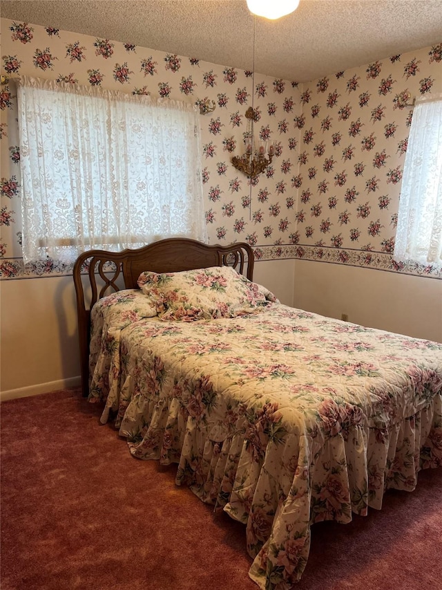 carpeted bedroom featuring a textured ceiling, wallpapered walls, and baseboards