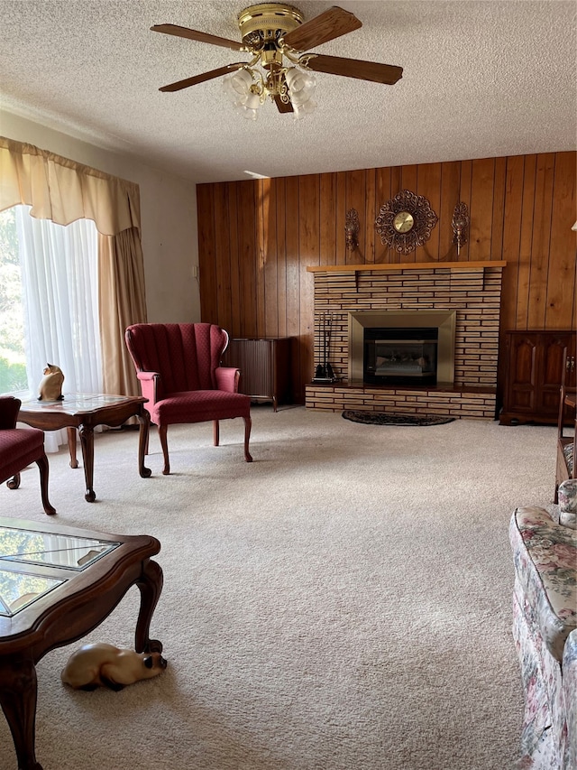 living room featuring ceiling fan, carpet floors, wooden walls, and a fireplace