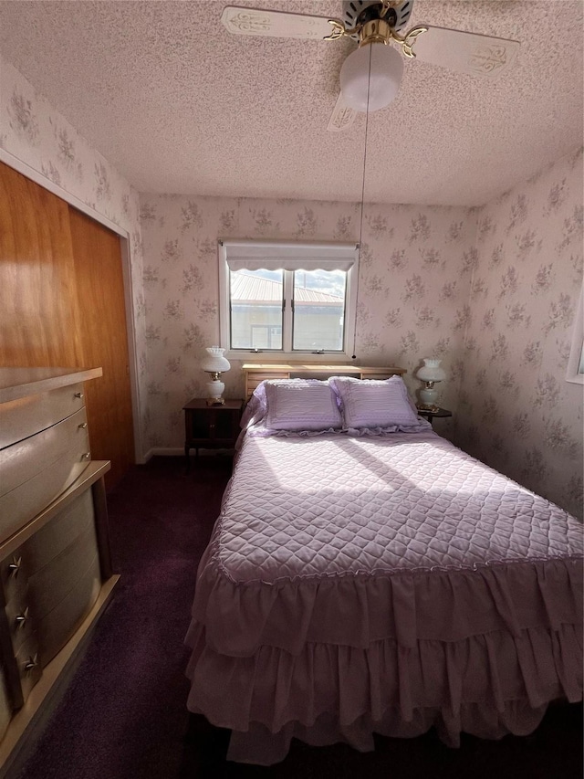bedroom with dark colored carpet, a textured ceiling, wallpapered walls, and ceiling fan