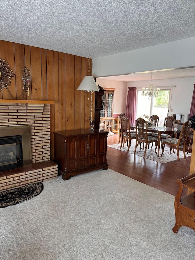 233 4th Ave SW, Cut Bank, MT 59427 - living room featuring a chandelier, carpet floors, a glass covered fireplace, a textured ceiling, and wood walls