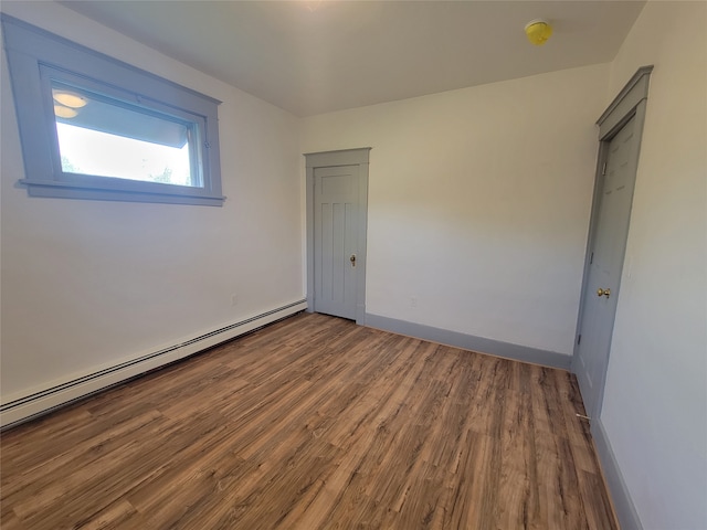 empty room with a baseboard heating unit and hardwood / wood-style flooring