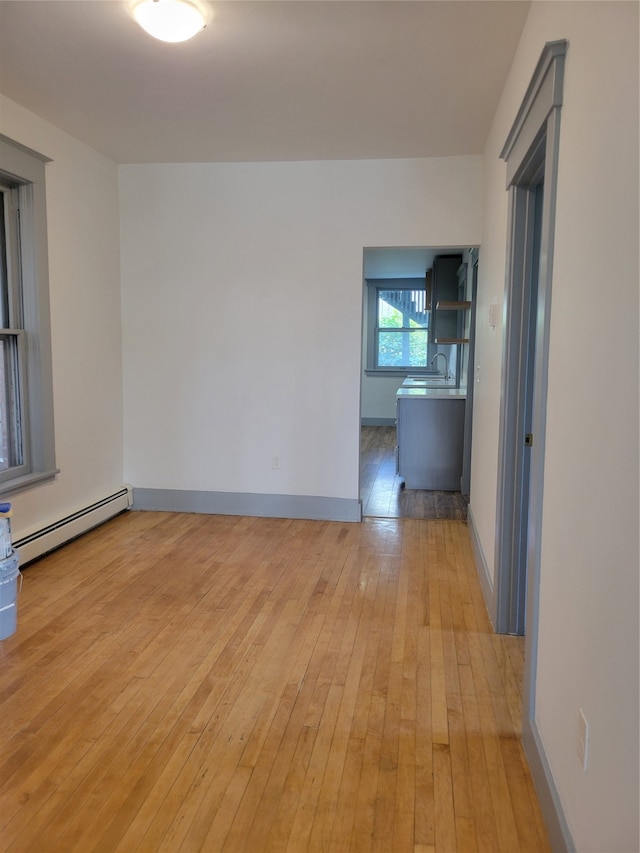 empty room featuring sink, light hardwood / wood-style flooring, and a baseboard radiator