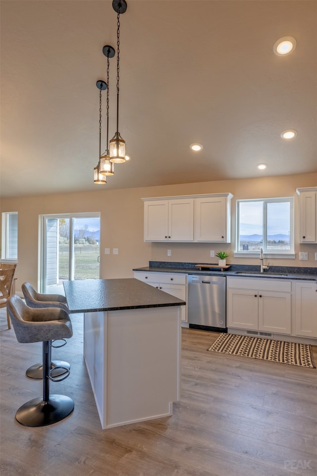 kitchen with stainless steel dishwasher, sink, white cabinets, and plenty of natural light