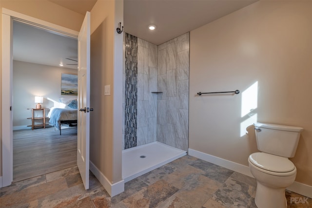 bathroom with toilet, hardwood / wood-style flooring, and a tile shower