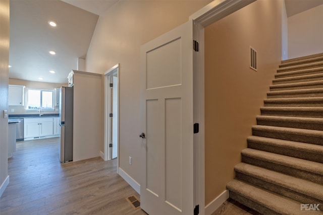 staircase with hardwood / wood-style flooring, sink, and vaulted ceiling