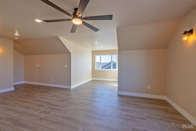 additional living space featuring light hardwood / wood-style floors, vaulted ceiling, and ceiling fan